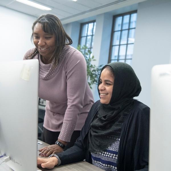 两个数字媒体研究生看着电脑屏幕，面带微笑.